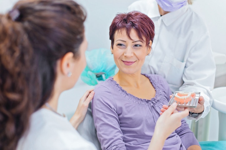 Dentiste montrant des prothèses dentaires à un patient centre dentaire boncelles